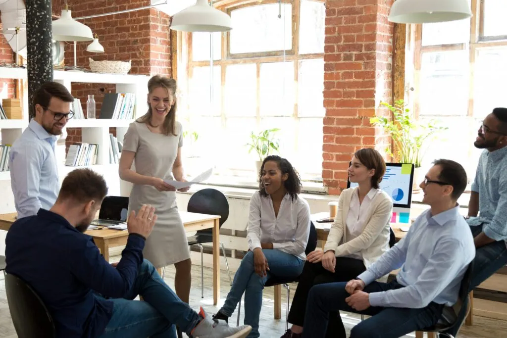 Cinco oficinistas se sientan casualmente en una reunión. Las tiendas para empleados mantienen a los empleados comprometidos y felices.