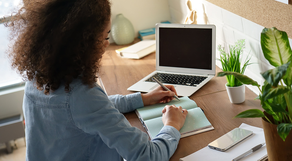 Femme assise à un bureau prenant des notes.