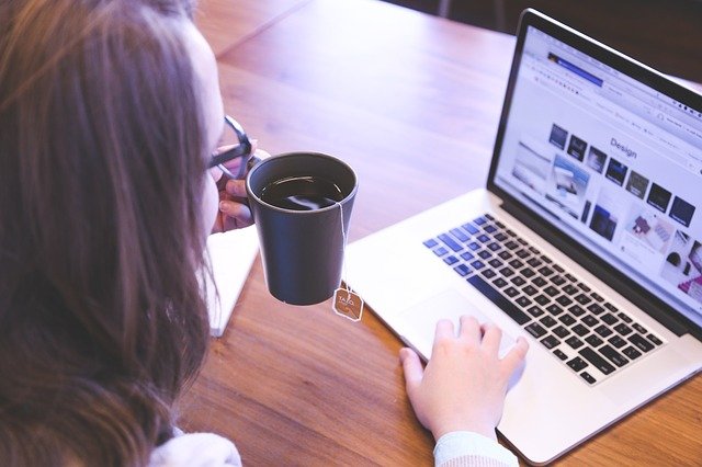 Mulher olhando para um laptop enquanto bebe chá