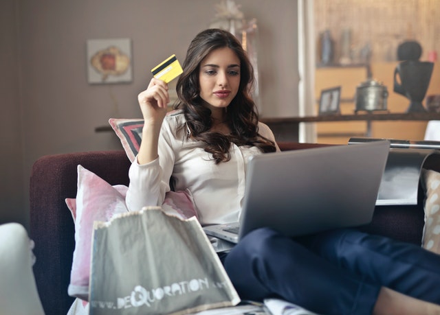 ノートパソコンで買い物をしているときにクレジットカードを持っている女性
