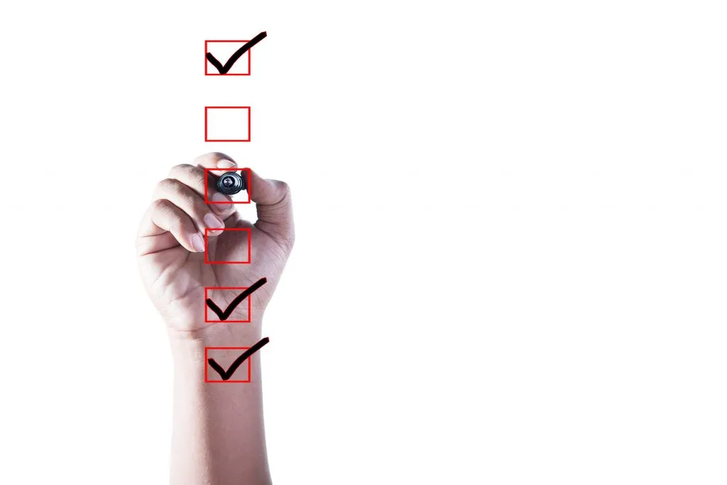 Lista de verificare pentru optimizarea site-ului ilustrată de o mână folosind un marcator negru pentru a bifa casetele