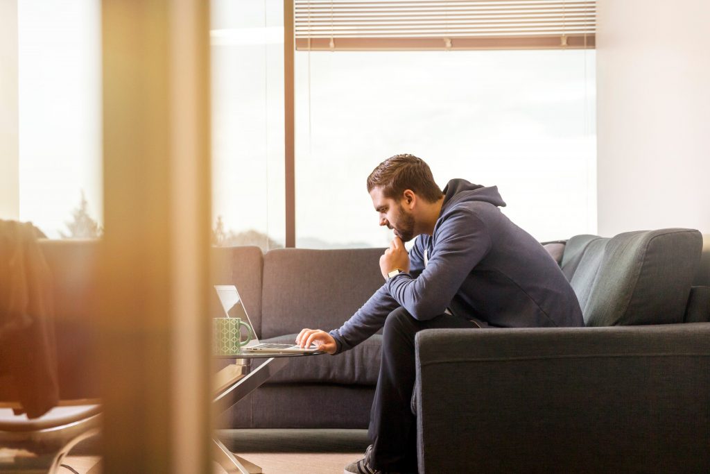 Um homem examinando um laptop - Como criar uma campanha de Natal de comércio eletrônico - Copify blog
