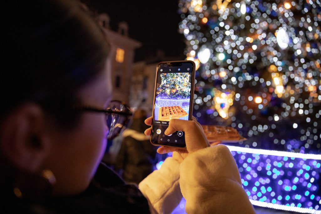 Imagine cu cineva care face o fotografie cu un brad de Crăciun pe un telefon - Cele mai bune campanii de Crăciun în rețelele sociale - Copify blog