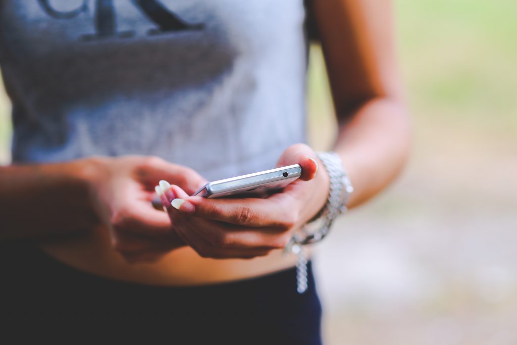 Image d'une jeune femme utilisant un smartphone - Comment rédiger un texte publicitaire efficace sur Facebook - Blog COPify