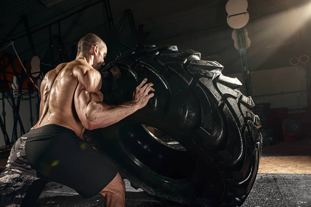 Hombre musculoso volteando neumático