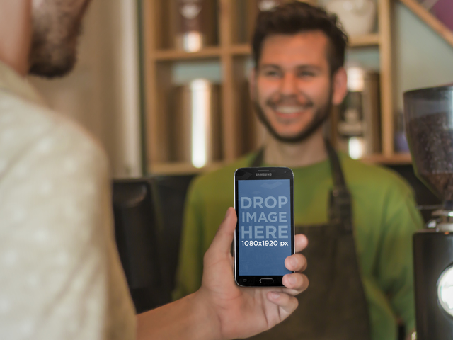Jeune homme utilisant un téléphone Android au modèle de maquette de café Placeit Image de scène