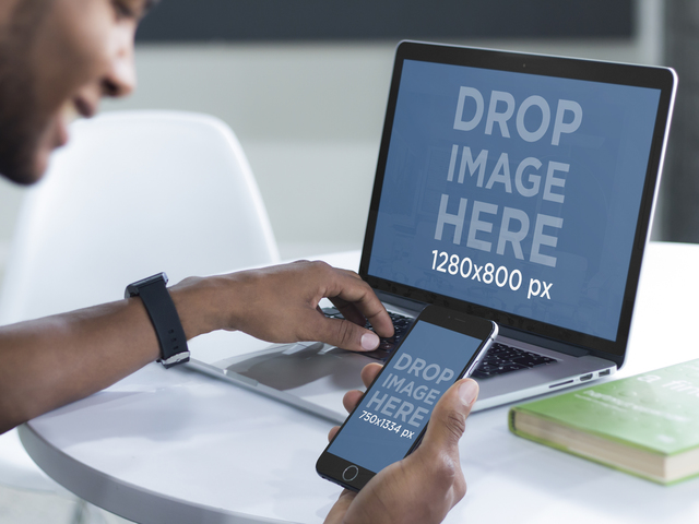 Jeune homme travaillant sur son ordinateur portable MacBook Pro et iPhone 6 Mockup Placeit Stage Image