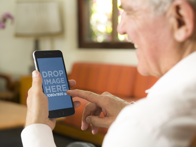Mockup-Vorlage eines älteren Mannes mit iPhone 6 Plus zu Hause Placeit Stage Image
