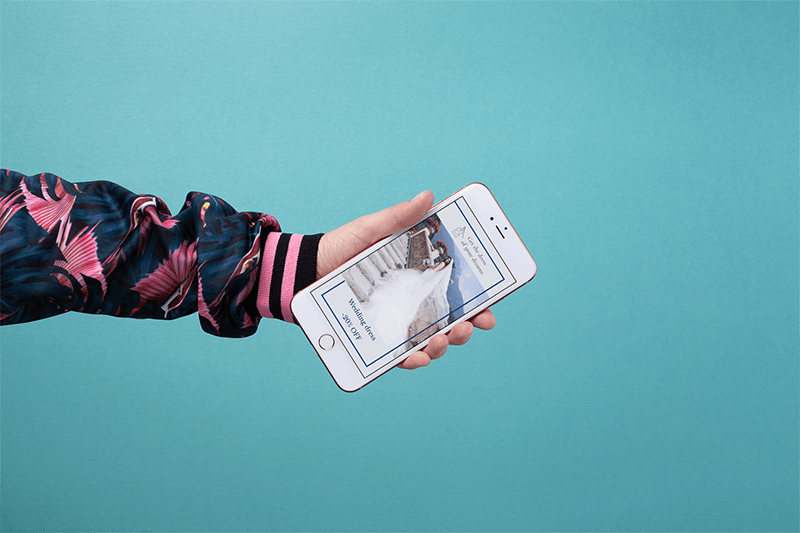 Modell eines bunt gekleideten Arms, der ein goldenes Iphone hält