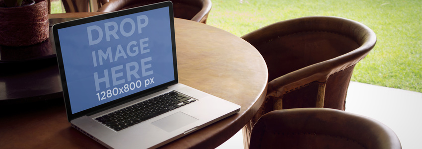 كمبيوتر محمول نموذج بالحجم الطبيعي لجهاز MacBook على طاولة طعام خارجية في الفناء وضع صورة مسرحية
