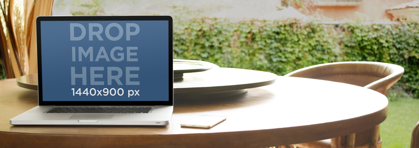 كمبيوتر محمول نموذج بالحجم الطبيعي يتميز بجهاز Macbook فوق طاولة طعام في صورة مرحلة Garden Placeit