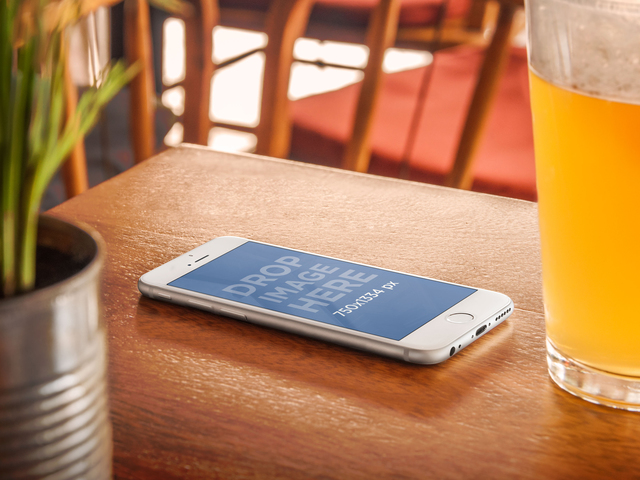 Maquete do produto, iPhone 6 na mesa de madeira ao lado de uma imagem de palco de cerveja Placeit
