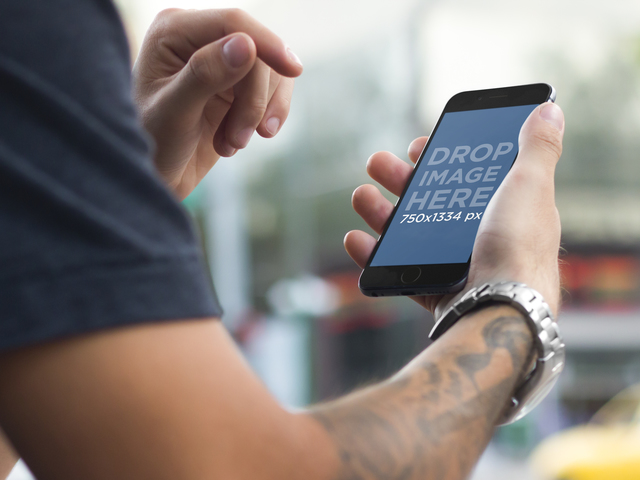 Jovem tatuado em ambiente urbano usando uma imagem de palco Placeit de maquete do iPhone 6