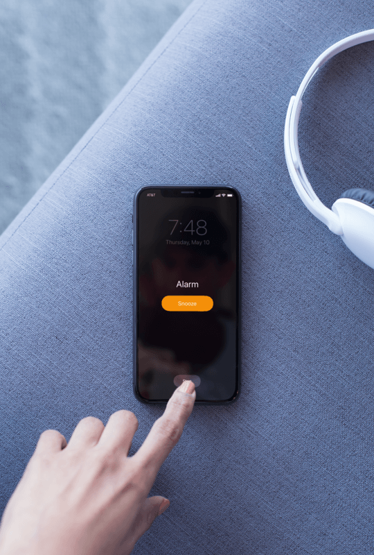 Machetă a unui iPhone X care se odihnește pe o canapea redând un podcast