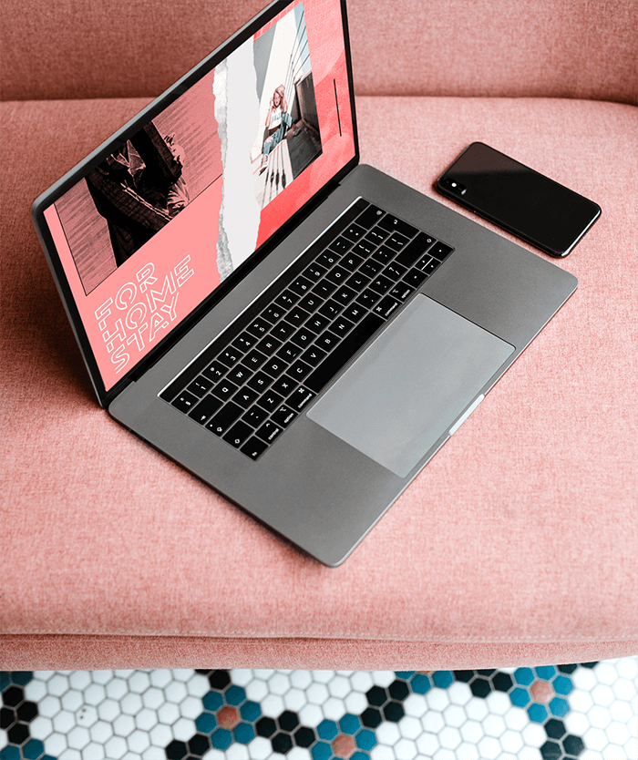 Maquette d'un Macbook à côté d'un téléphone sur un canapé rose