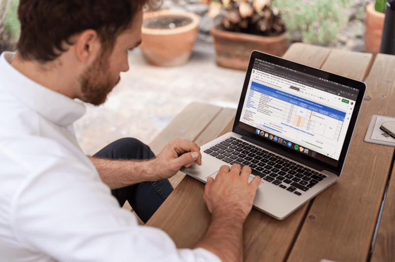 رجل يستخدم نموذج Macbook على مقعد خشبي
