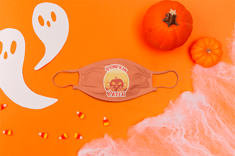 Modell einer Gesichtsmaske, die zwischen einigen Halloween-Ornamenten platziert ist