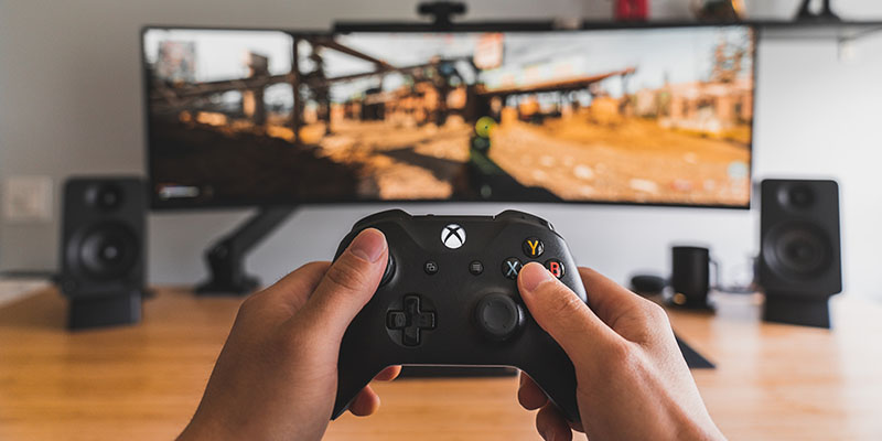 コントローラーを持って大画面でビデオ ゲームをプレイしている男性