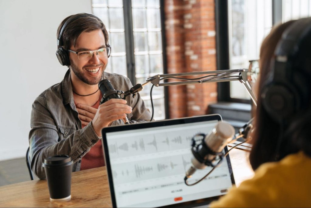 Dois jovens profissionais gravando um podcast em um escritório com paredes de tijolos.