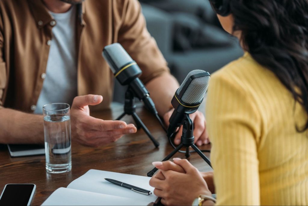 Um homem e uma mulher gravando um podcast juntos.