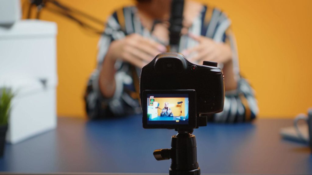 Uma profissional de negócios gravando um podcast e filmando a si mesma em uma câmera digital.