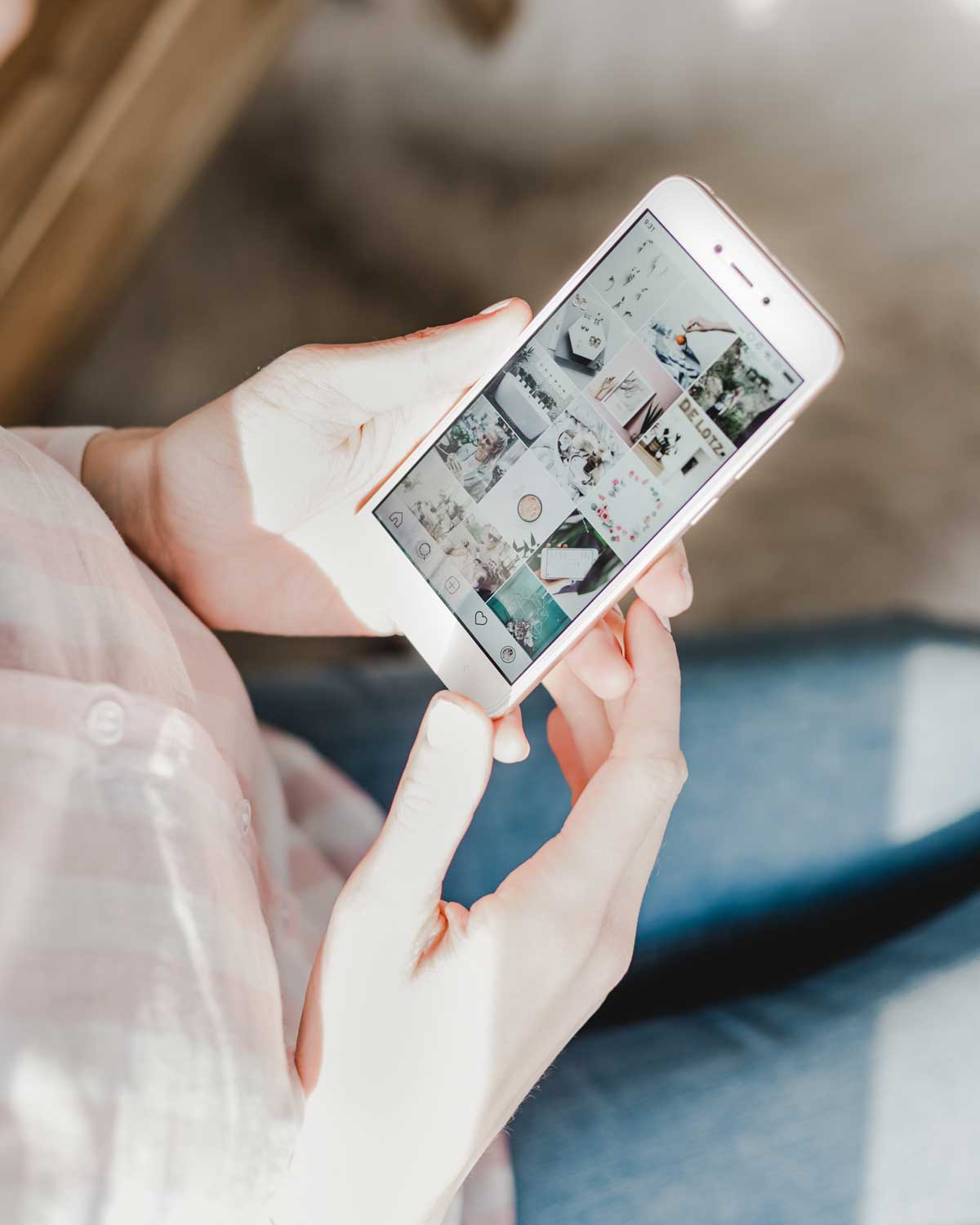 gambar tangan yang diterangi matahari memegang pgone dengan aplikasi instagram terbuka.