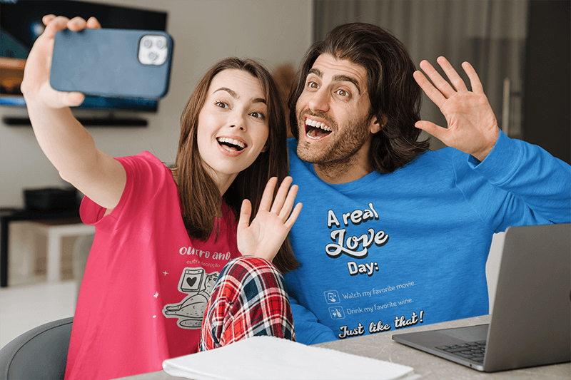 Modelo de camiseta e moletom de um casal sorridente tirando uma selfie em casa