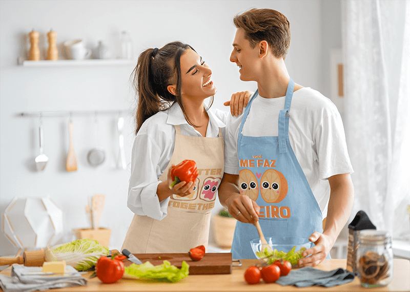 Maquete de avental apresentando um casal feliz de chefs fazendo uma salada