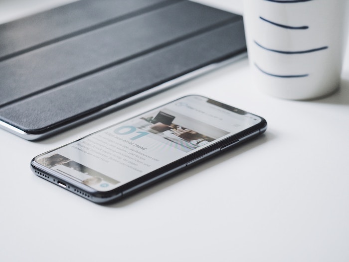 um smartphone, ipad e um copo em uma mesa branca