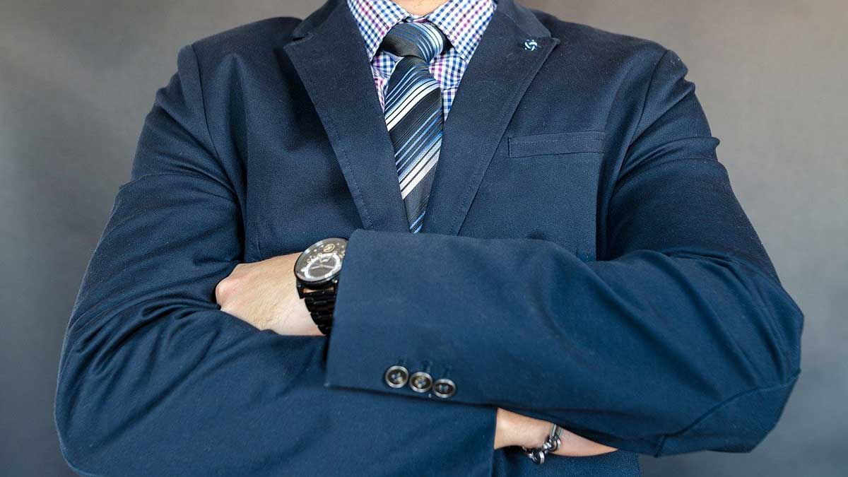 primer plano de la principal en traje de negocios azul con los brazos cruzados, luciendo fuerte.