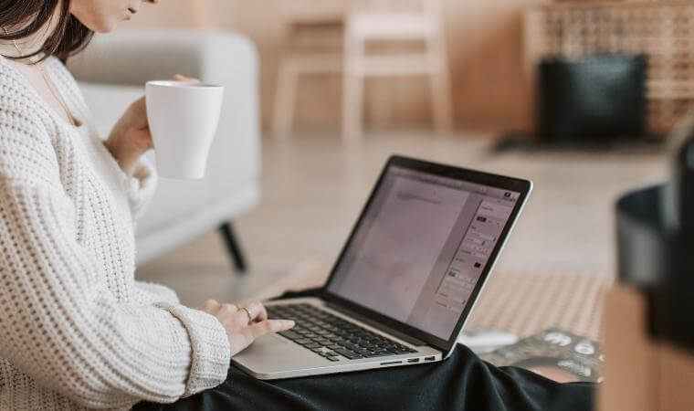 Frau, die auf einem Computer schreibt und Kaffee trinkt