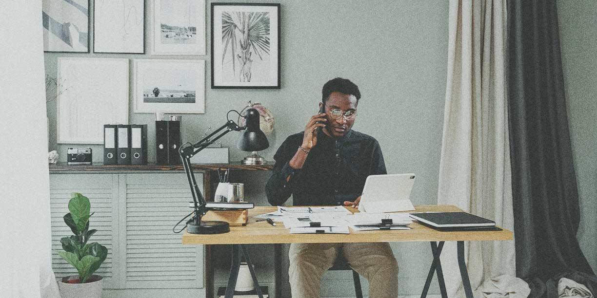 Pria berbaju hitam duduk di kantor rumahnya bekerja di meja