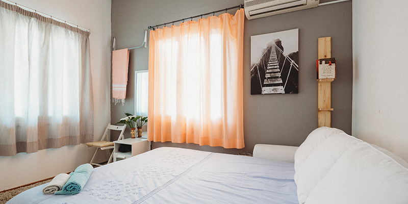 Kamar bersih dengan layar oranye dan tempat tidur putih