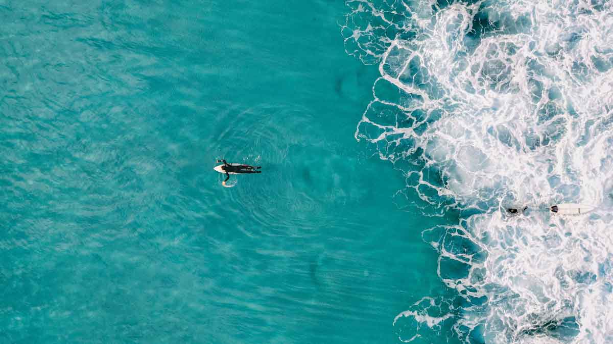 samudra biru pirus dengan peselancar berenang ke laut.