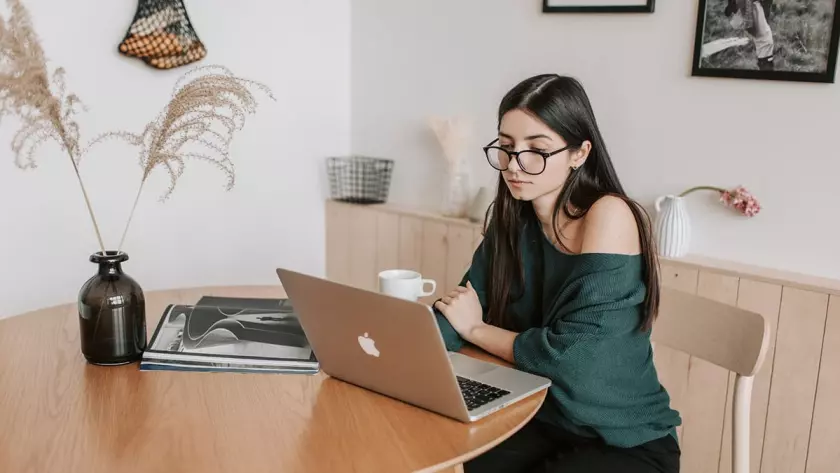 Una donna seduta a un tavolo con un laptop pensa alla lead generation per la sua startup.