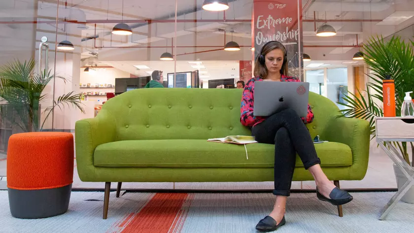 Una donna seduta su un divano verde pianifica le strategie di lead generation per la sua startup.