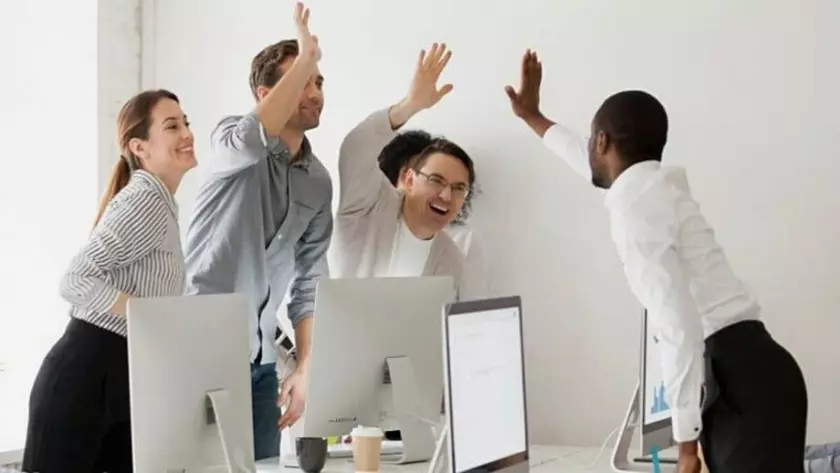 Un gruppo di persone alza le mani in aria in un ufficio dopo aver generato un lead di successo per la loro startup.