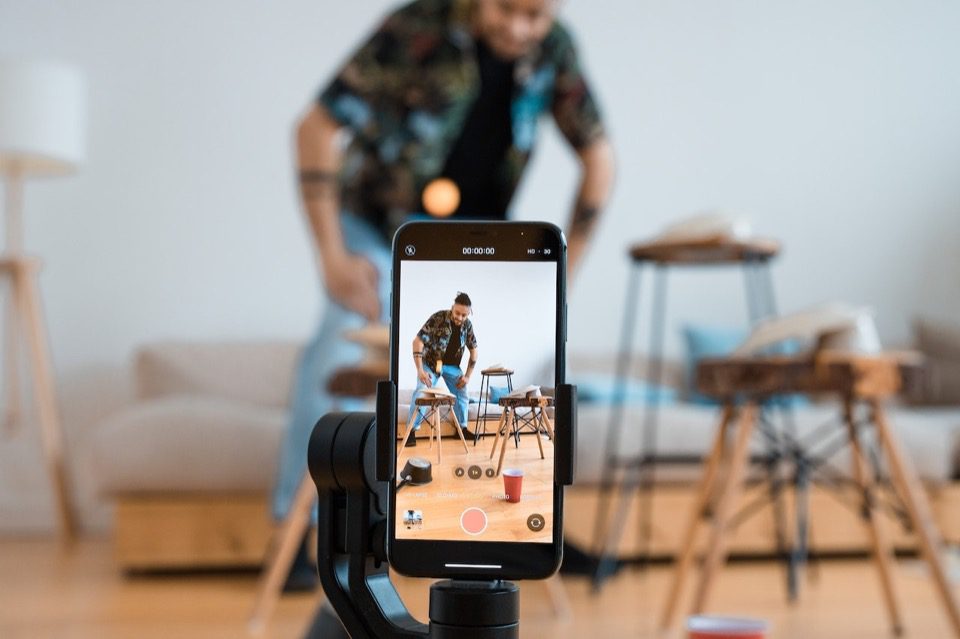Persoană care filmează video folosind un telefon pe un trepied