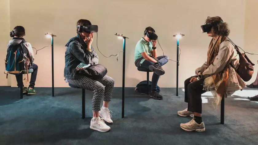 VR ヘッドセットを付けて部屋に座っている人々のグループ。