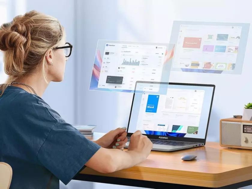 Une femme assise à un bureau avec un ordinateur portable ACEMAGIC AX15 devant elle.