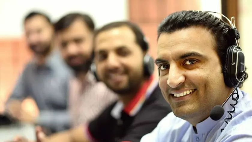 Eine Gruppe Männer mit Headsets in einem Callcenter.