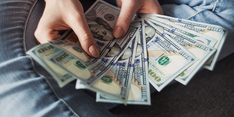 Due mani che mostrano una diffusione di banconote da un dollaro