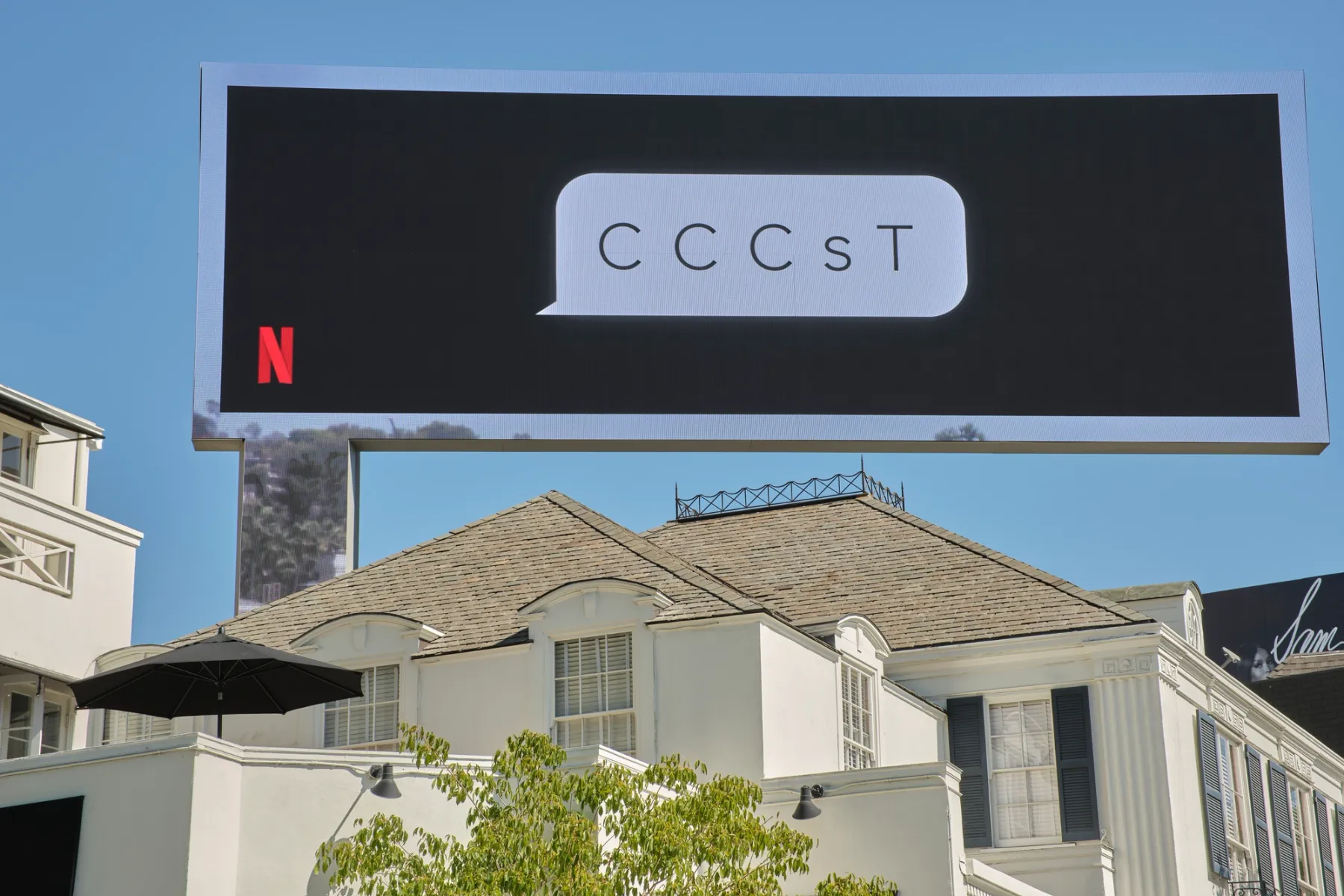 Фотография рекламного щита. У i9t есть логотип Netflix в левом нижнем углу и облачко с надписью «CC C C s T».