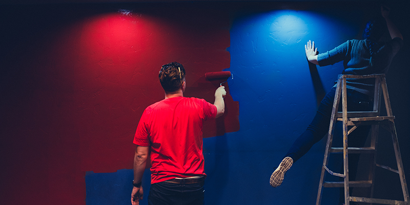 Un hombre y una mujer pintando una pared azul de rojo.